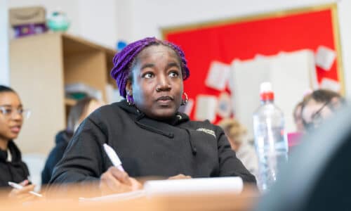 Adult student in classroom writing notes